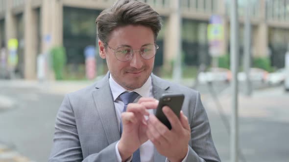 Middle Aged Businessman Browsing Internet on Smartphone