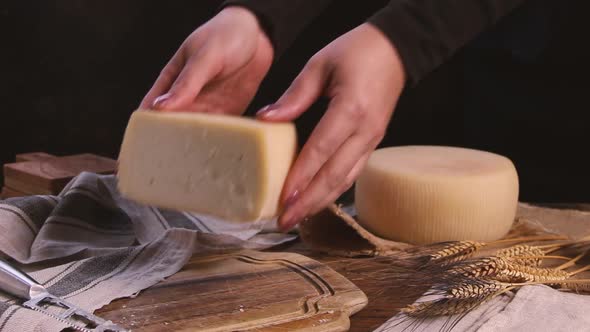 Women hands put pieces of  fresh homemade cheese on a wooden board close up