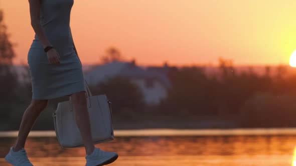 Young Woman Walking Alone on Lake Shore Walkway on Warm Evening