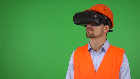 A Young Construction Worker Uses VR Glasses - Green Screen Studio - He Looks Around