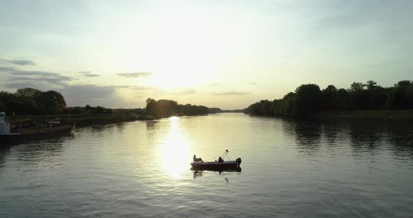 Aerial view of a small boat crossing Drava river at sunset, Osijek, Croatia.