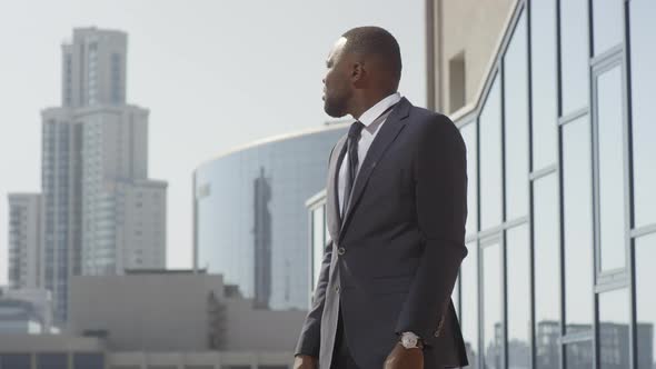 Afro Businessman Looking At Wristwatch Outdoors