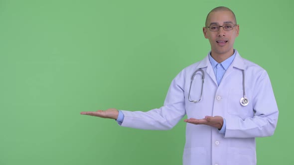 Happy Bald Multi Ethnic Man Doctor Showing Something and Giving Thumbs Up