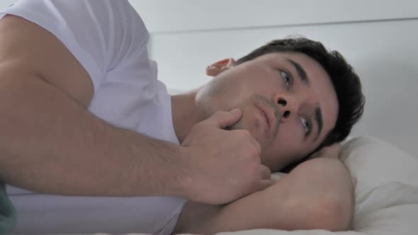 Young Man Thinking While Lying in Bed