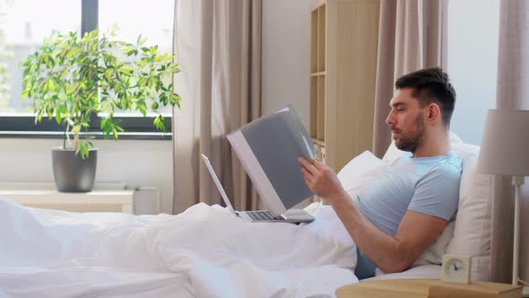 Man with Laptop Working in Bed at Home Bedroom