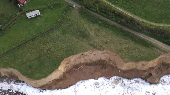 An aerial shot from a drone that starts looking down at high tide hitting sea defences and pans up t