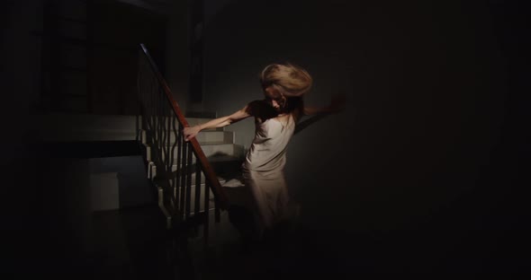 Scared Woman In A Nightgown Runs Up The Stairs Running Away From Home. Domestic Violence