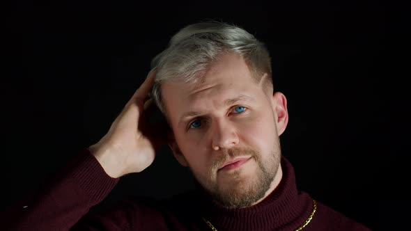 Smiling Cheerful Young Man in Trendy Stylish Clothes Holding Hand Over Head Looking at Camera