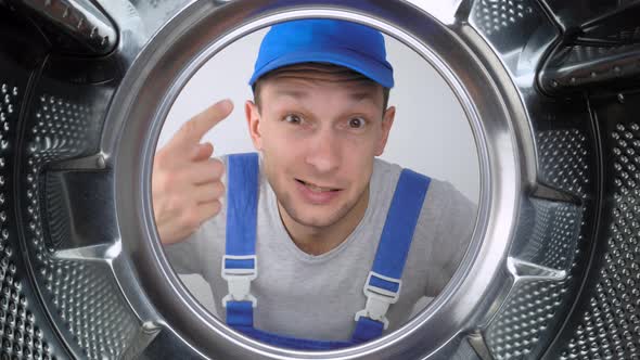 home appliance repairman sticks his head in drum of washing machine and screams