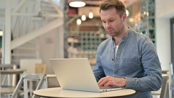 Casual Man with Back Pain Using Laptop in Cafe 