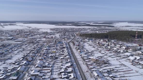 Aerial view of village with forest, fields and roads.