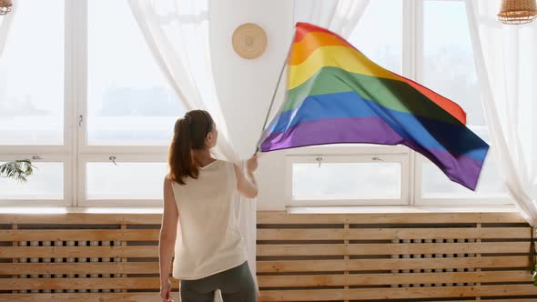 Female Holding LGBT Gay Flag in Hands and Waving on Sunset in Sunny Rays