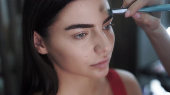 Artists Hands Applying Makeup to a Beautiful Twenty Fiveyearold Brunette