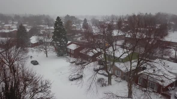 Aerial rise over snow covered houses in a residential neighborhood.