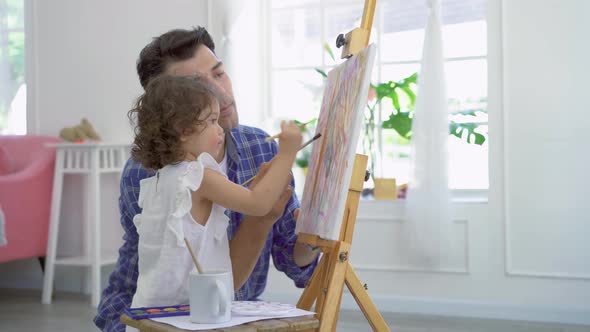 Happy family of father and kid drawing picture, using different paints and brushes. Lesson of art.