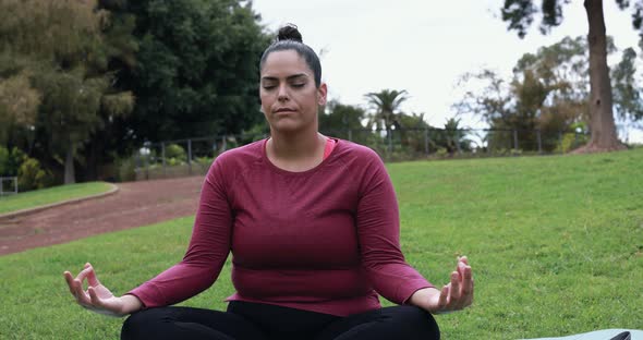 Young curvy woman doing yoga exercises outdoor