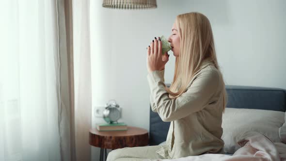 Positive blond woman drinking water