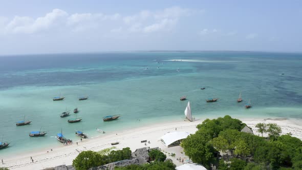 Boats anchoring in shallow tropical coastal ocean waters, drone shot.