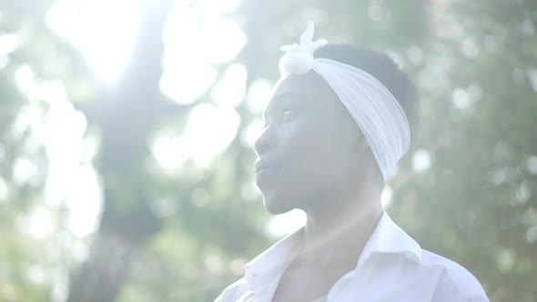 Side View Young Slim African American Woman in Sunbeam at Background of Green Trees in Spring Summer