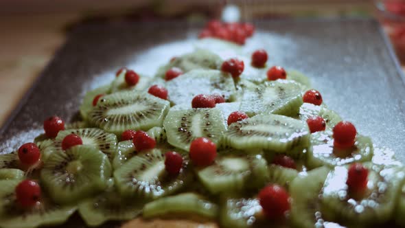 Juicy Fresh Kiwi Slices and Frozen Red Currant Arranged in a Shape of Christmas Tree on a Black