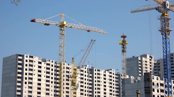 Yellow Cranes and Highrise Buildings on Blue Sky Background