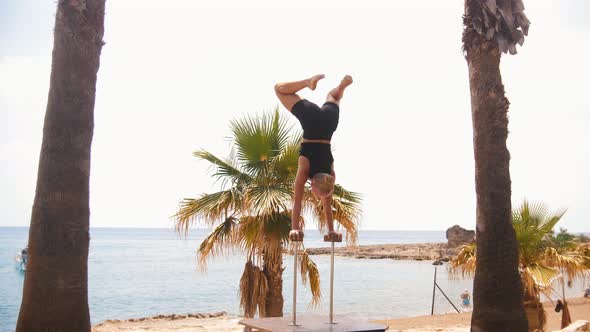 Gymnastics By the Sea a Young Blonde Woman Doing a Handstand on the High Small Beams and Moving Her