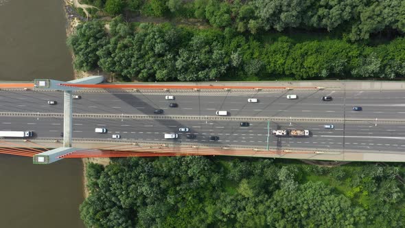 City caring at highway bridge on background smooth river surface drone view