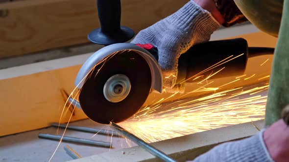 A builder's hands in work gloves cut a metal hairpin with an angle grinder electric tool. Preparatio