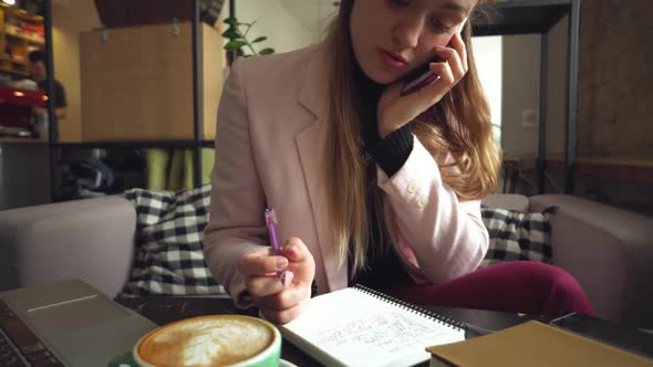 Businesswoman Working Remotely Talking on Mobile. Busy Businesswoman Working in a Cafe Talking on