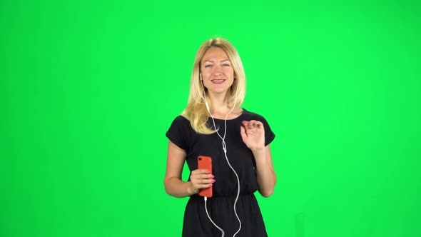 Cheerful Girl Walks in Headphones and with a Smartphone, Switches Music and Dancing, Chroma Key