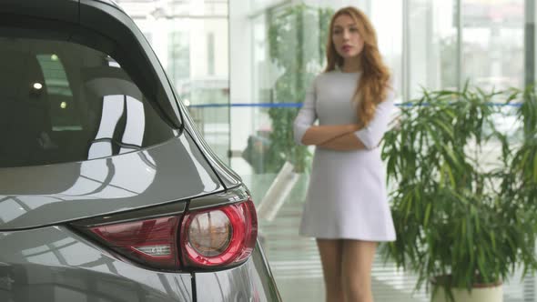 Beautiful Woman Thinking While Choosing a New Car at the Dealership