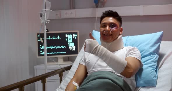 Bandaged Male Patient Showing Thumb Up and Smiling Lying in Hospital Bed