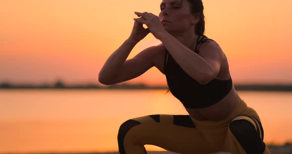 A Woman Performs sitUPS at Sunset on the Beach in Slow Motion