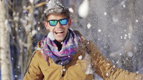 Glamorous Young Man Throwing Snow Up in Front of Camera