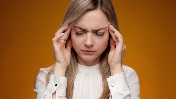 Young Woman Has Headache Standing Against Blue Background