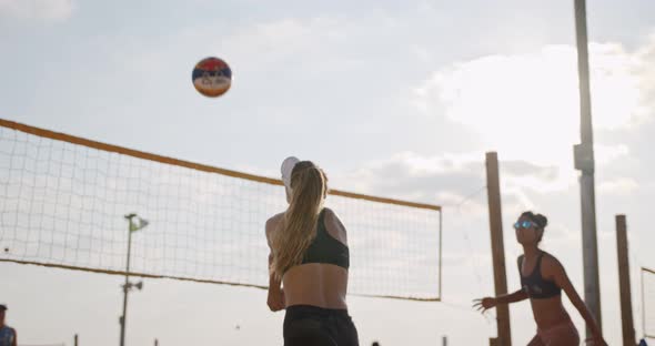 Slow motion of women playing beach volleyball during sunset