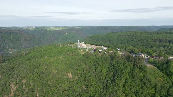 The white roller coaster of an amusement park on top of a steep hill towering above the moselle rive