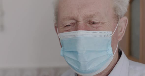 Close Portrait of Grandfather with Mask Looking Into Camera with Sad Eyes Indoor