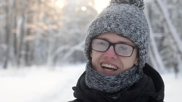 man with misted glasses  in winter snow forest. knitted hat and scarf.