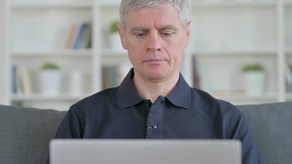 Middle Aged Businessman with Laptop Looking at Camera