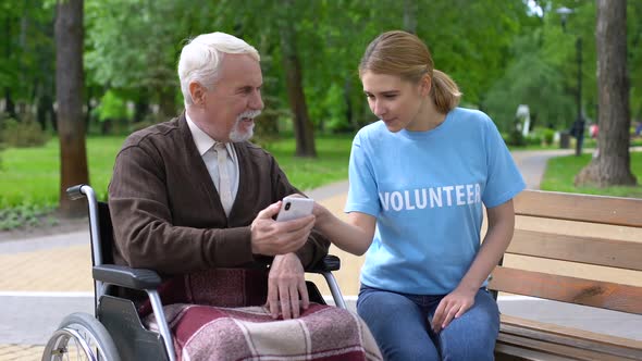 Female Volunteer Helping Disabled Old Man Use Smartphone Nursing Home Charity