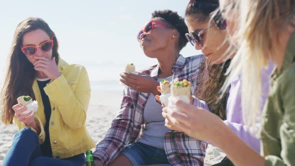 Happy group of diverse female friends having fun, having picnic at the beach