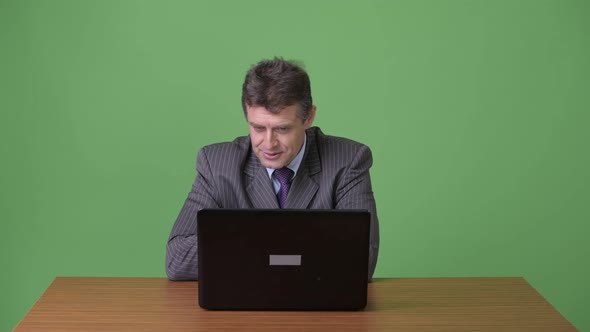 Mature Handsome Businessman Against Green Background