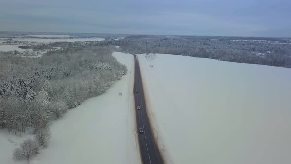 Drone. Coniferous forest, road and village. Asphalt. Winter landscape.