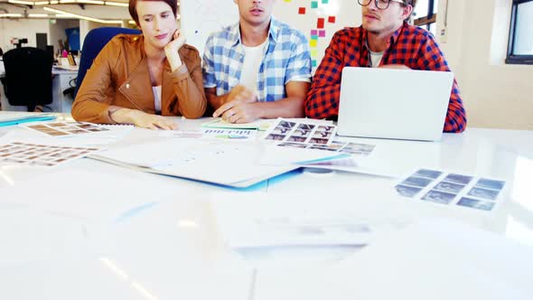 Graphic designer holding photo sample and interacting with colleagues