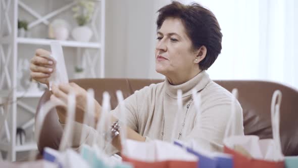Side View of Dazed Brunette Middleaged Woman Looking at Bills Holding Head in Hands