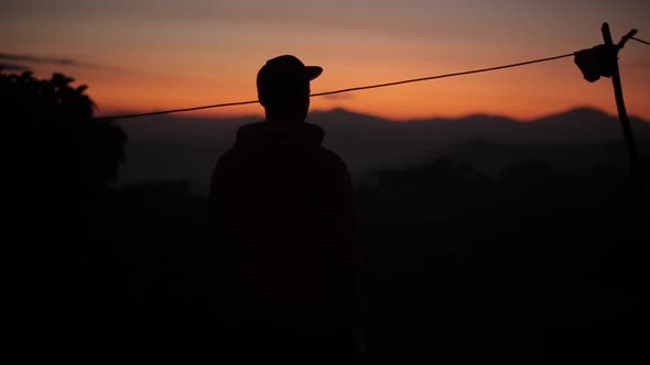 A Silhouette of a Young Man at Sunset, Sunrise in Asia, Nepal. Mountains, Village.