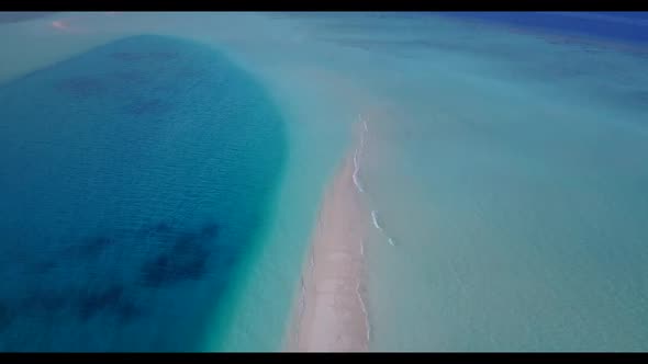 Aerial drone shot scenery of tropical tourist beach holiday by blue green ocean with bright sandy ba