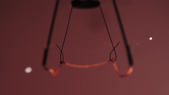 The Tungsten Filament in a Glass Lamp Closeup in Slow Motion on Red Background