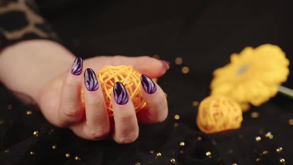 Adult Woman's Hand with Purple Manicure on Black Background